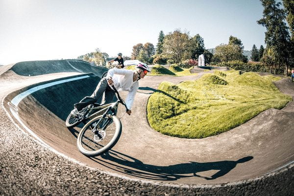 Zwei Fahrradfahrerinnen in der Kurve eines Pumptracks. 