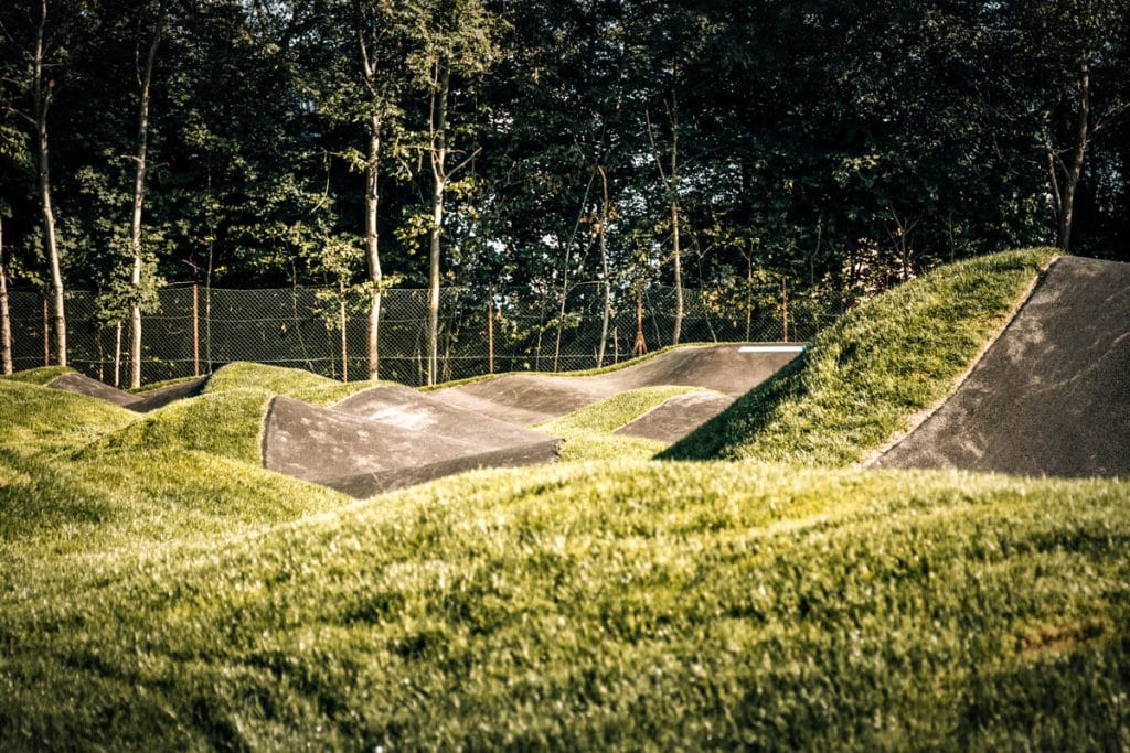 Welchen und Kurven von einem Pumptrack mit grünem Gras im Vordergrund und entlang der Strecke. 