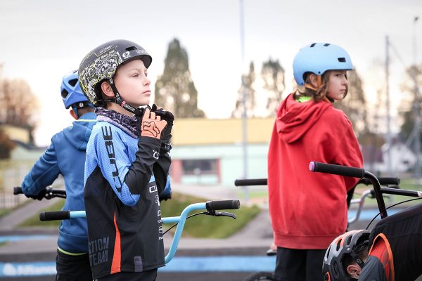 Kids puting on the helmets to start with a bike ride on a pump track.